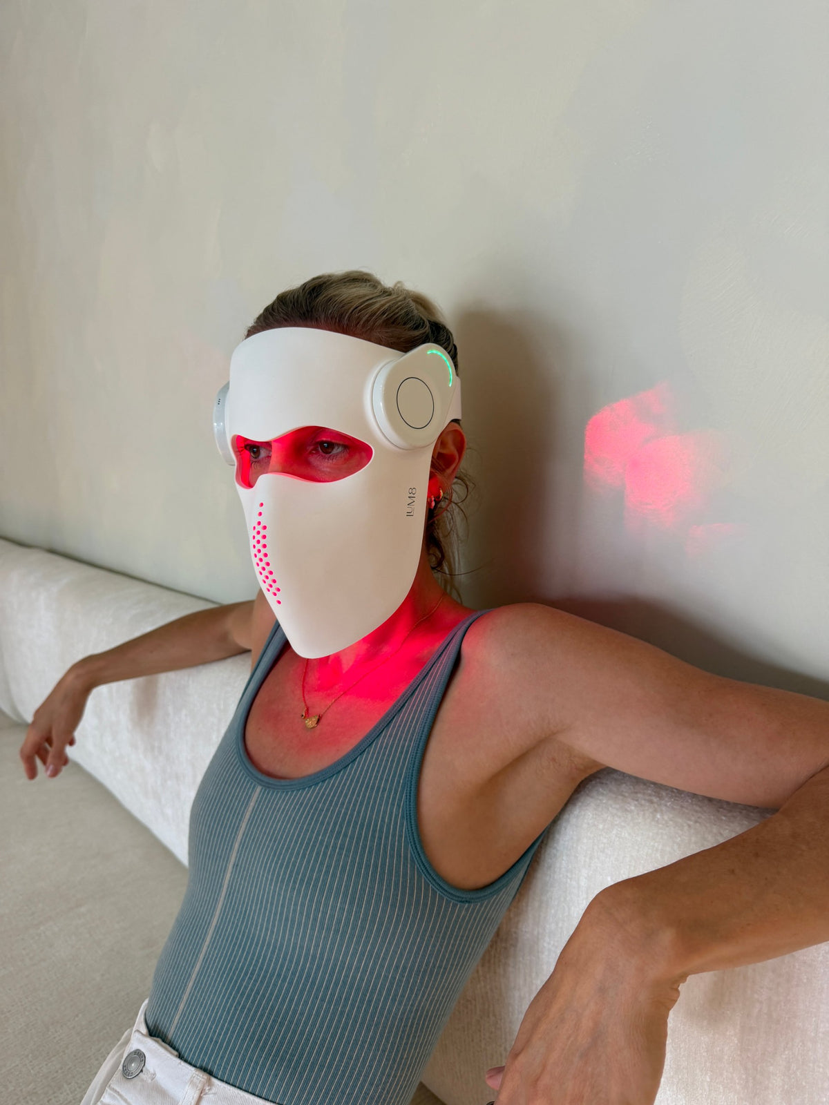 LUM8 ProLaser Face Mask glowing red, worn at home on the sofa