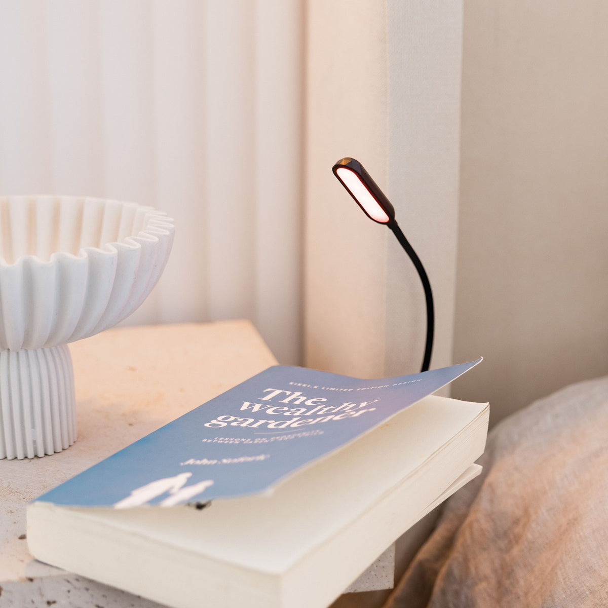 LUM8 Wind Down Reading Light clipped to book page — zero blue light sleep-safe reading lamp